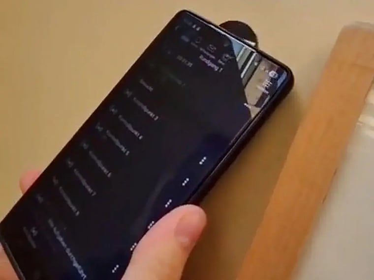 Hand mit Smartphone beim NFC-Kontrollpunkt-Scan an der Holzkante eines Schultisches
