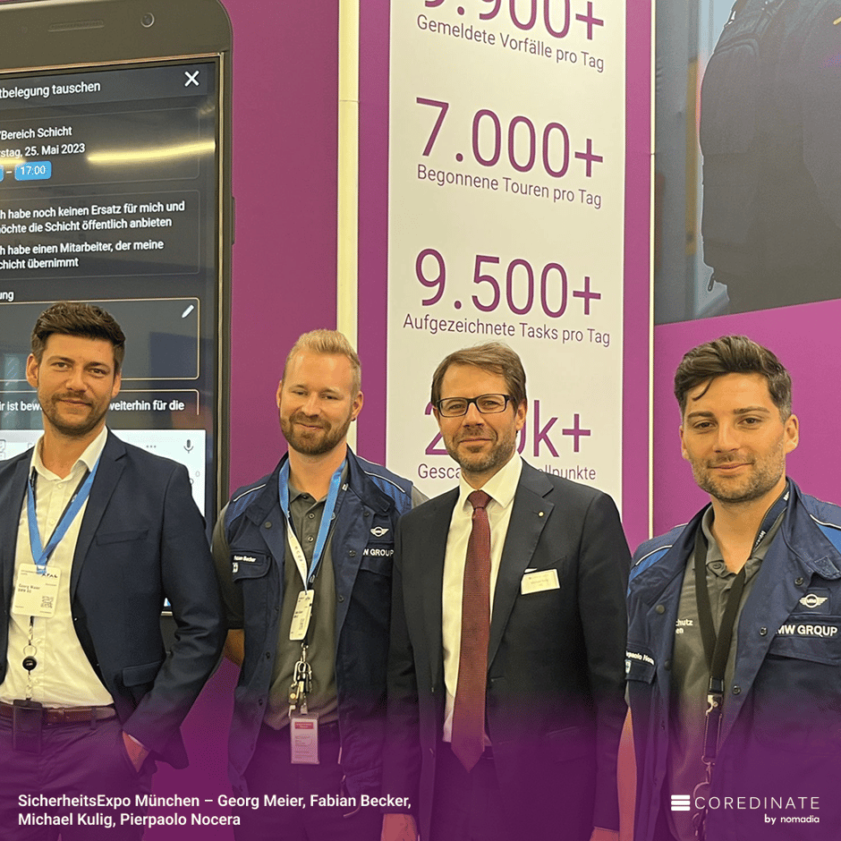 Four men (Georg Meier, Fabian Becker, Michael Kulig, Pierpaolo Nocera) smiling for a group photo at SecurityExpo Munich, in front of the purple COREDINATE® booth with task statistics displayed.