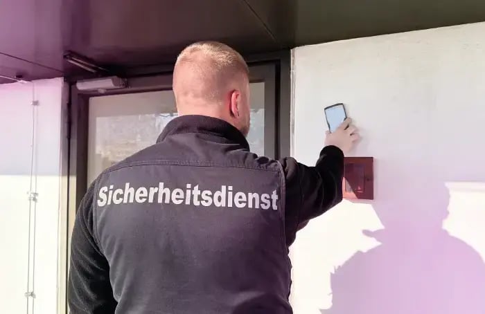 Security employee of UMG facilities GmbH scanning a COREDINATE checkpoint with his COREDINATE workforce management system app.