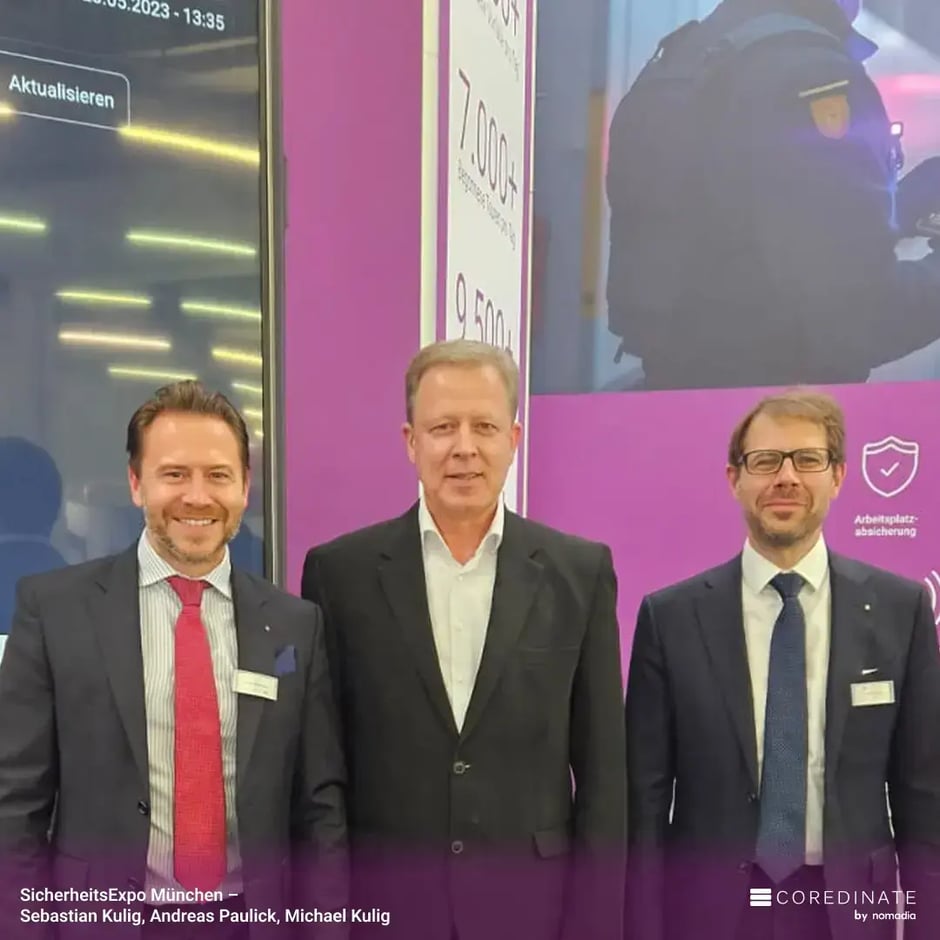 Sebastian Kulig, Andreas Paulick, and Michael Kulig standing side by side and smiling at the camera at the COREDINATE® booth at SecurityExpo Munich.