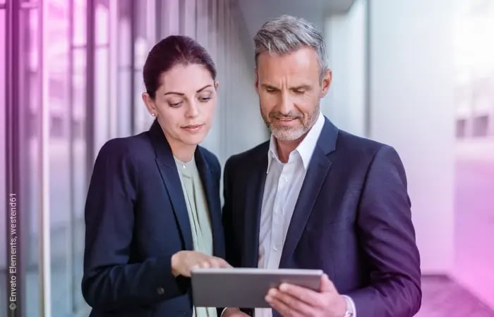 Frau und Mann als Geschäftspartner schauen gemeinsam auf Tablet