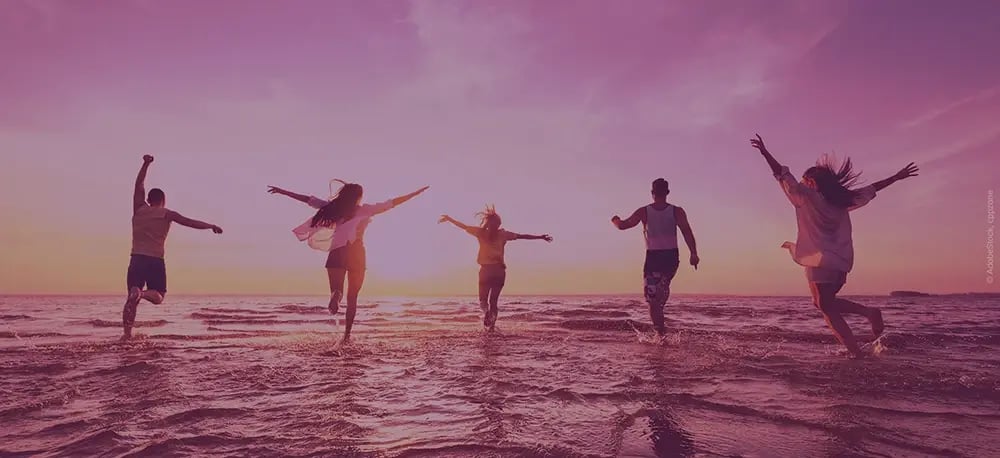 Fröhliche Menschen rennen ins Meer im Sonnenuntergang