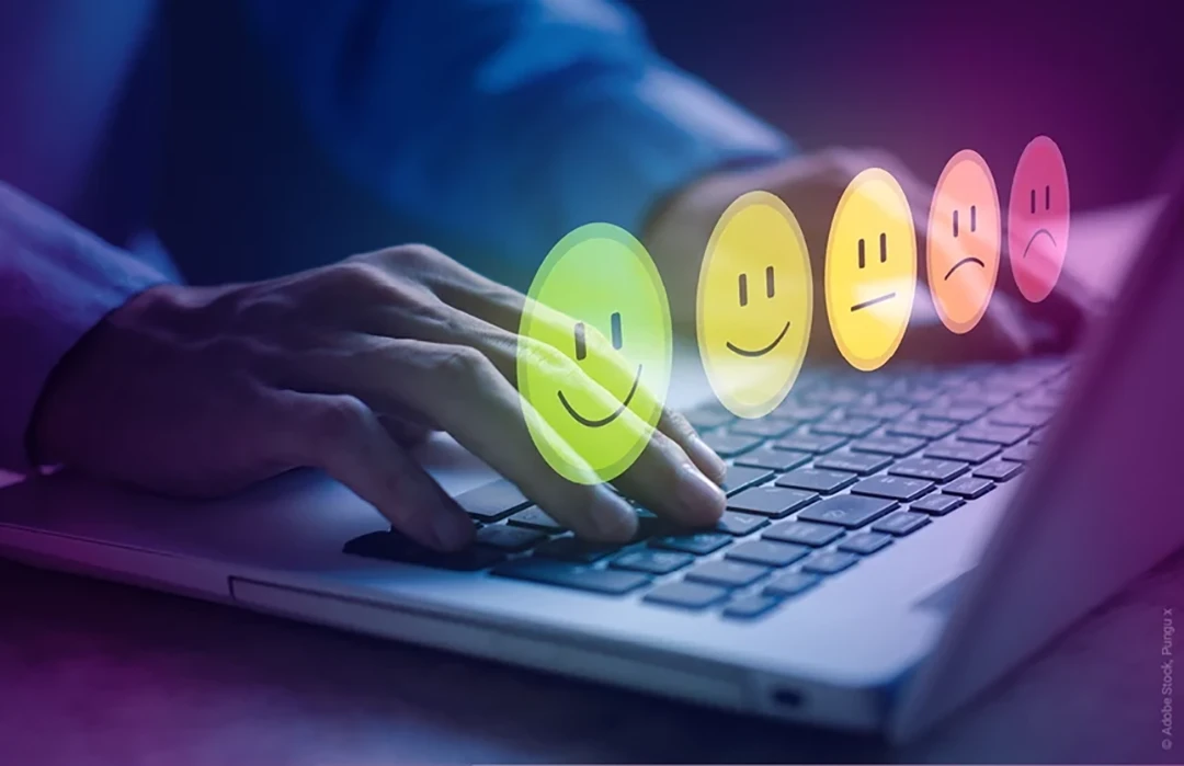 Eine Person am Laptop schreibt eine Bewertung mit Smileys und Stimmungen die den NPS Net Promoter Score symbolisieren