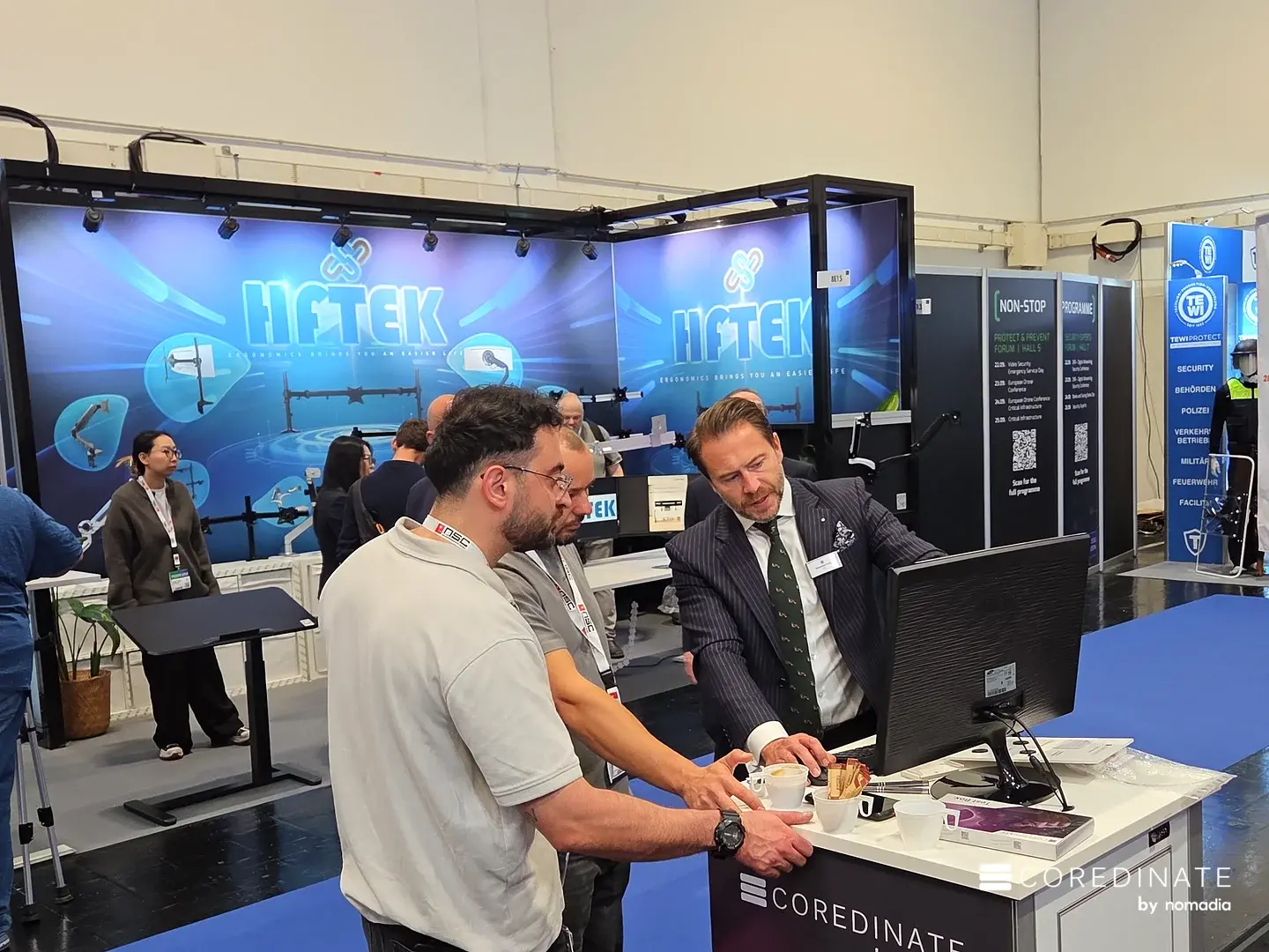 Sebastian Kulig im Gespräch mit Besuchern am Counter des COREDINATE-Stands
