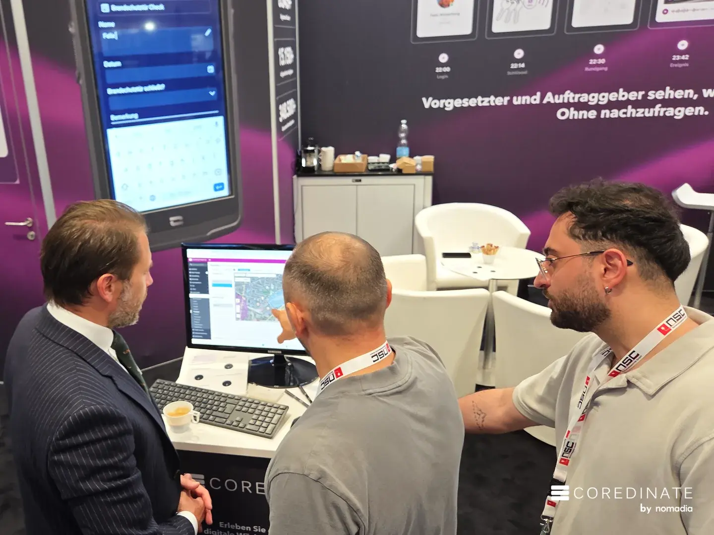 Sebastian Kulig zeigt zwei Besuchern das COREDINATE-Portal am Stand auf der Security Essen 2026