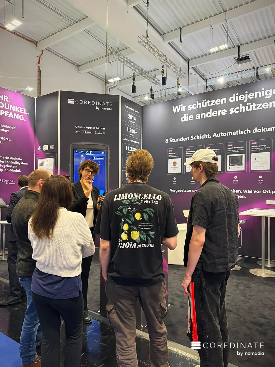 Beratung an der großen App-Anzeige am COREDINATE-Stand
