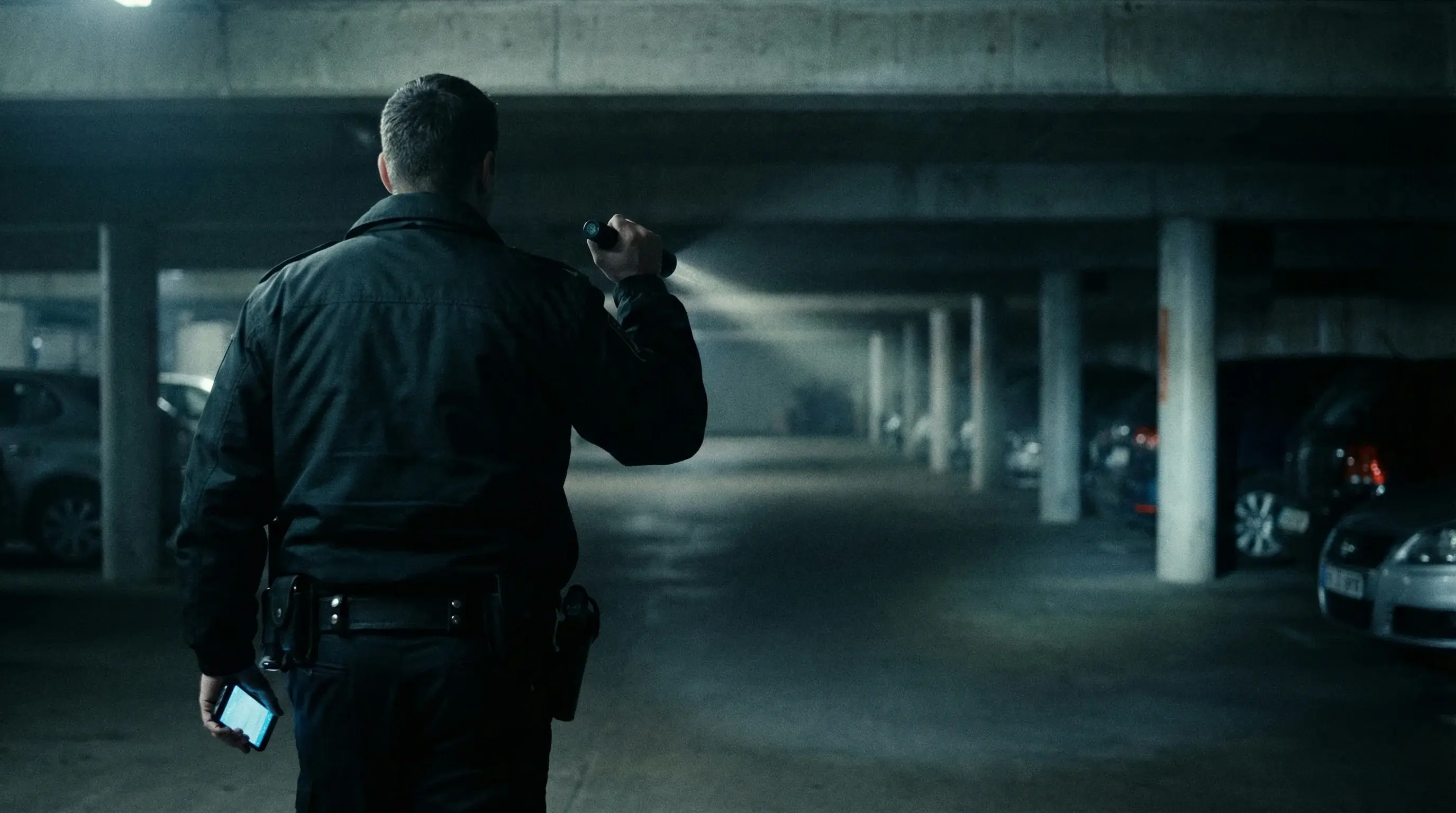 Kontrollgang eines Sicherheitsmitarbeiters in einer Tiefgarage mit Smartphone und COREDINATE Sicherheitsdienst App